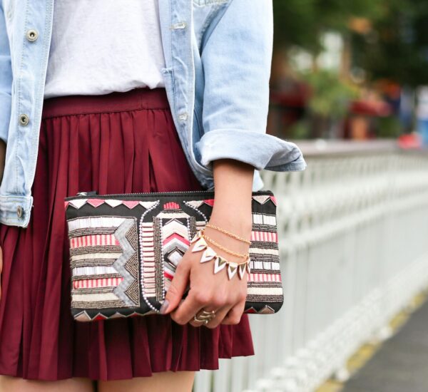 woman holding clutch bag standing beside white bridge